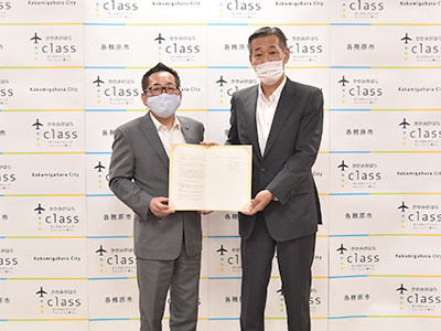 協定書を手にして立つ浅野市長らの写真